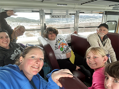 Adults on a school bus with happy students